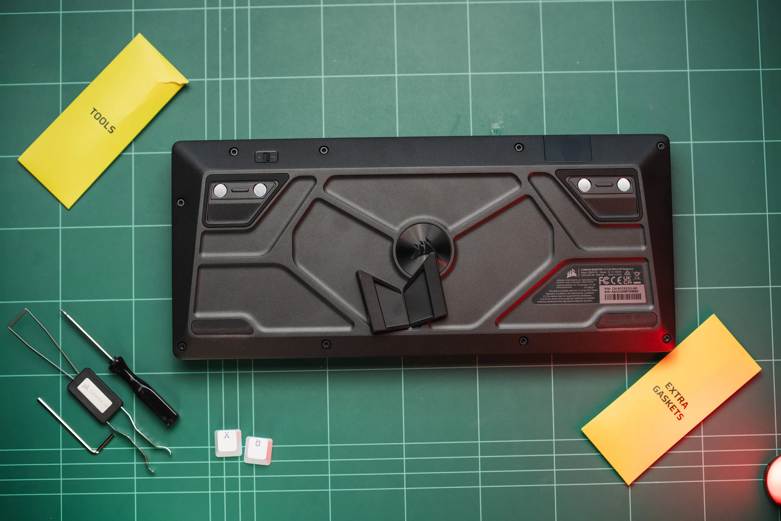 Undersiden av Corsair MAKR PRO 75 som viser den formede basen, de ni Torx-skruene, de magnetiske føttene og PC/Mac-bryteren