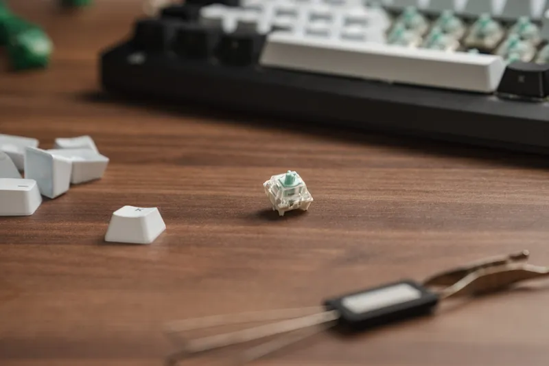 En enkelt Corsair MGX Hyperdrive-magnetbryter stående på et trebord ved siden av ekstra keycaps