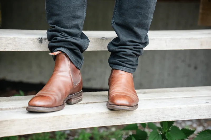 R.M. Williams Comfort Craftsman i brunt, til mørke jeans, sett forfra stående på en tretrapp