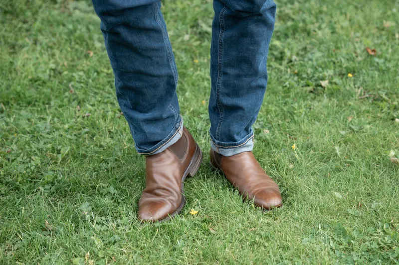 Brune R.M. Williams Comfort Craftsman til blå jeans, stående på gress