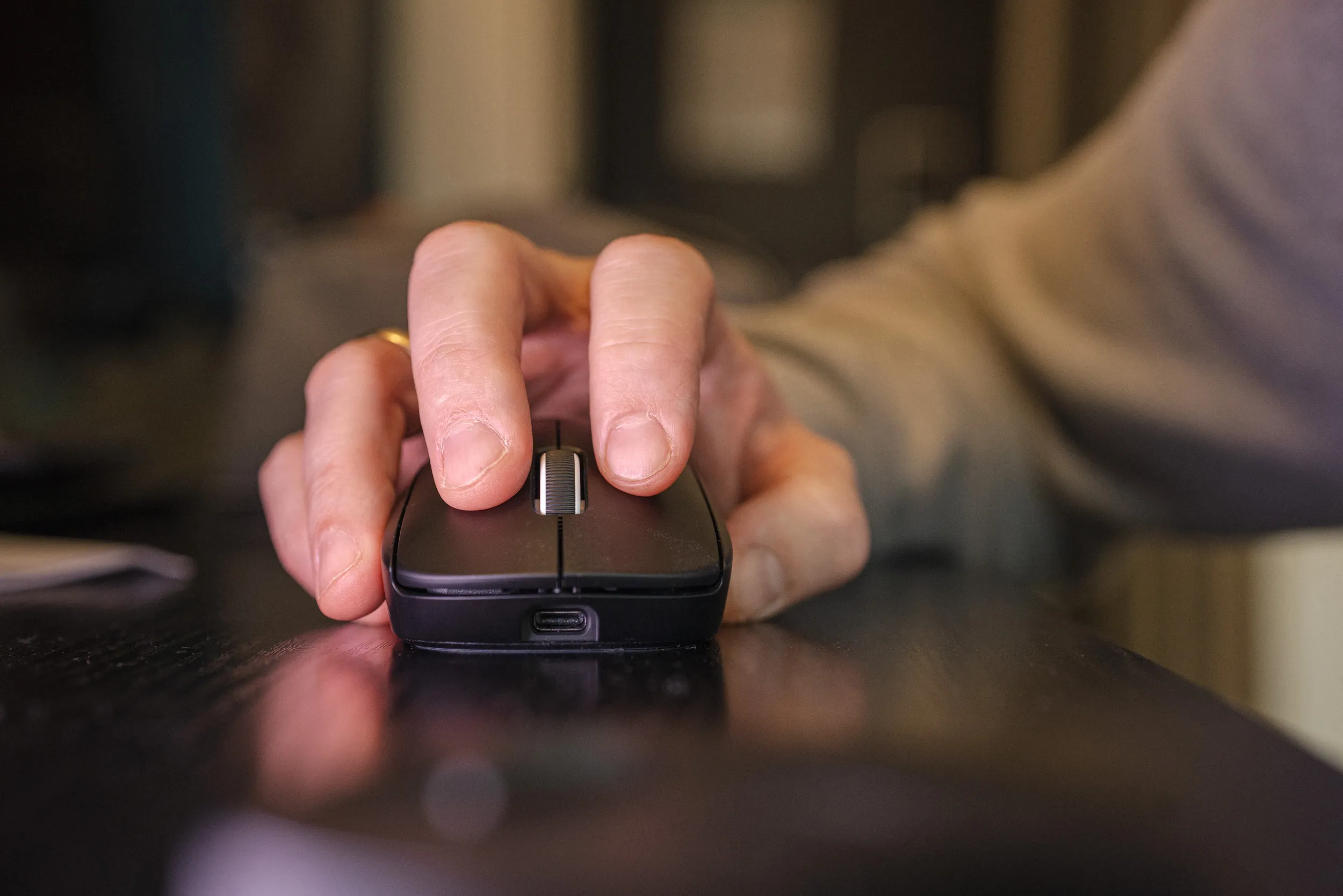 Hånd som holder Logitech G Pro X Superlight 2, sett forfra med USB-C-porten synlig