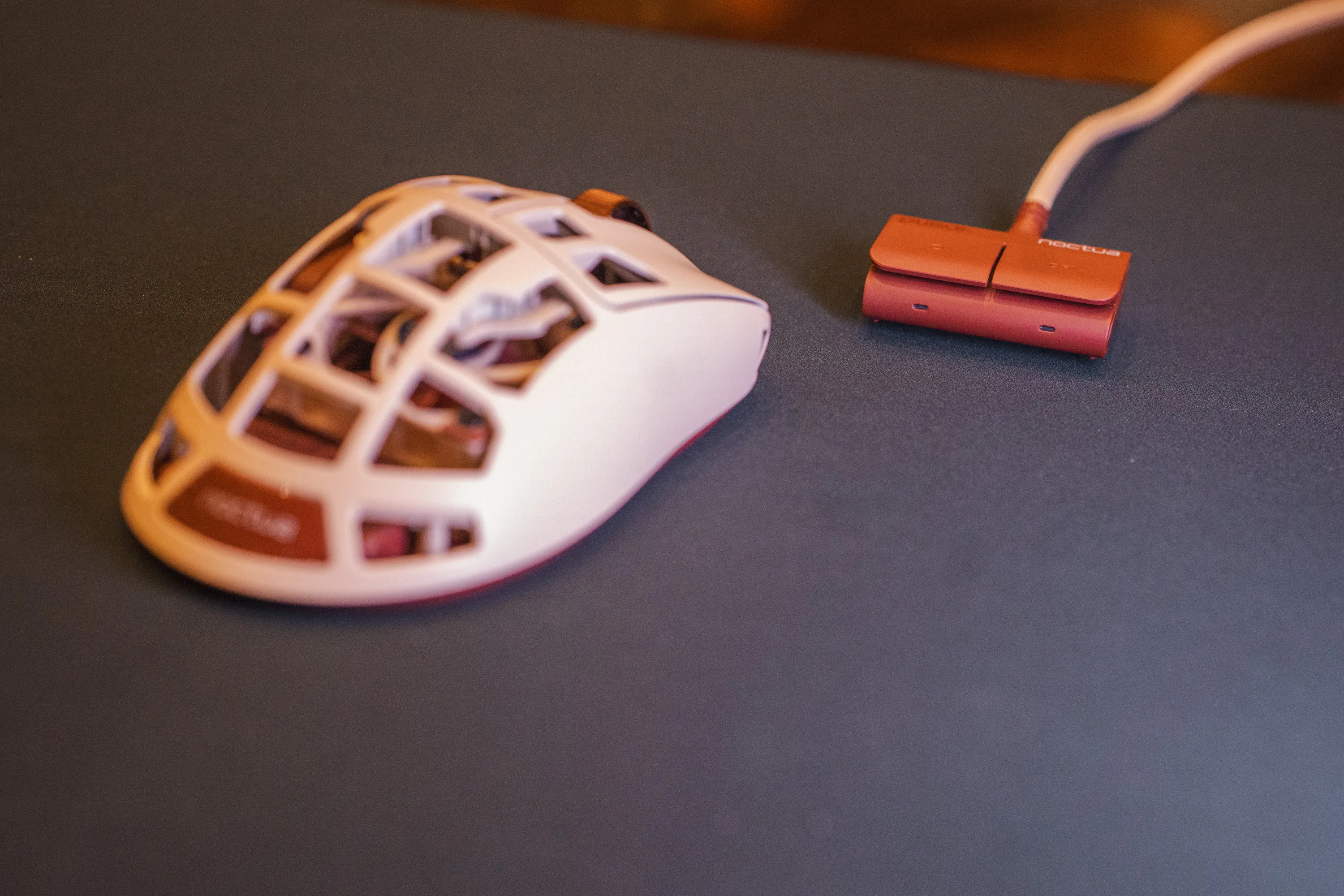 Feinmann F01 Noctua Edition og den brune mottakeren på en mørk musematte, fotografert lavt fra siden
