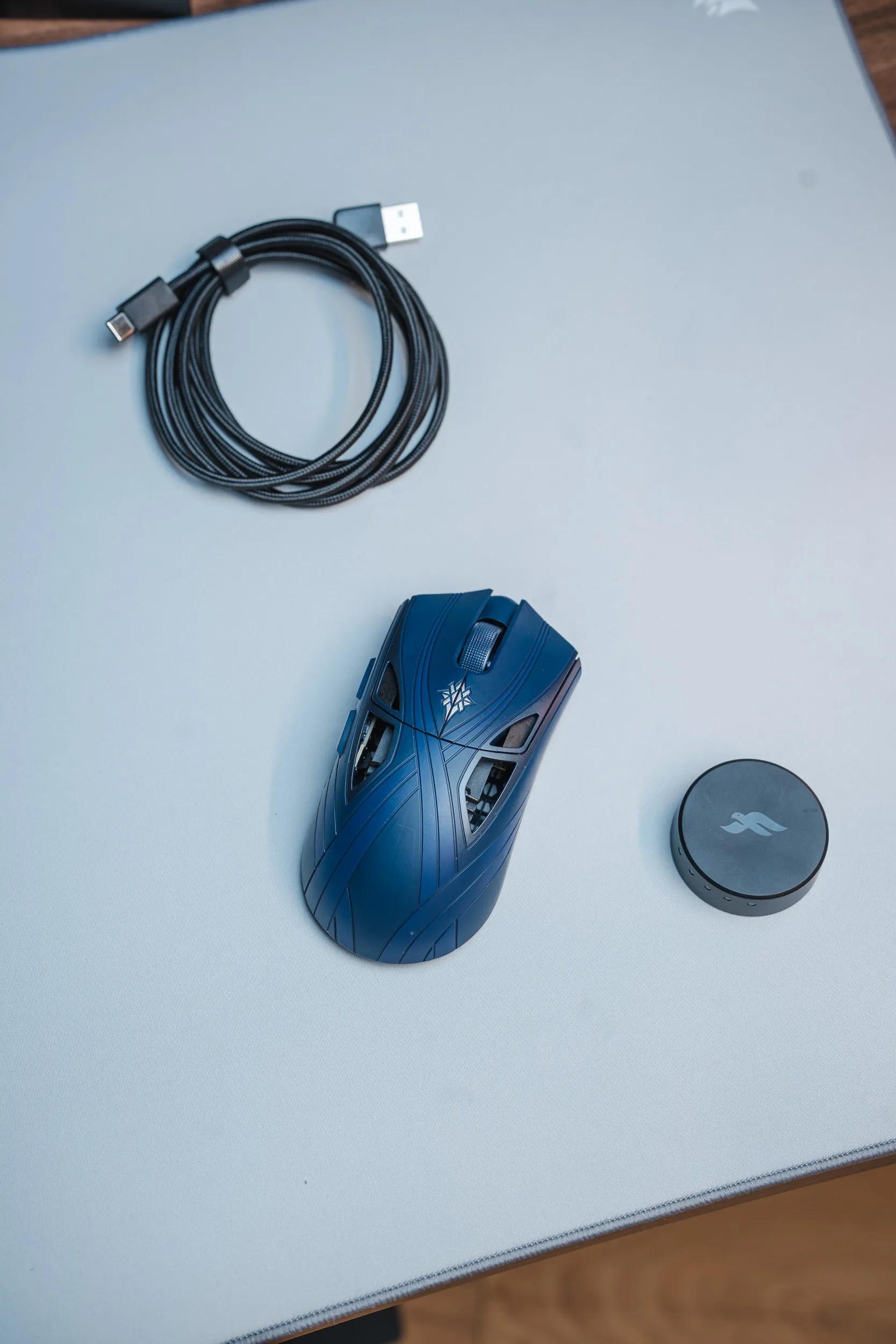 Finalmouse SLX Nightfall ved siden av den runde dongelen og en flettet USB-C-kabel