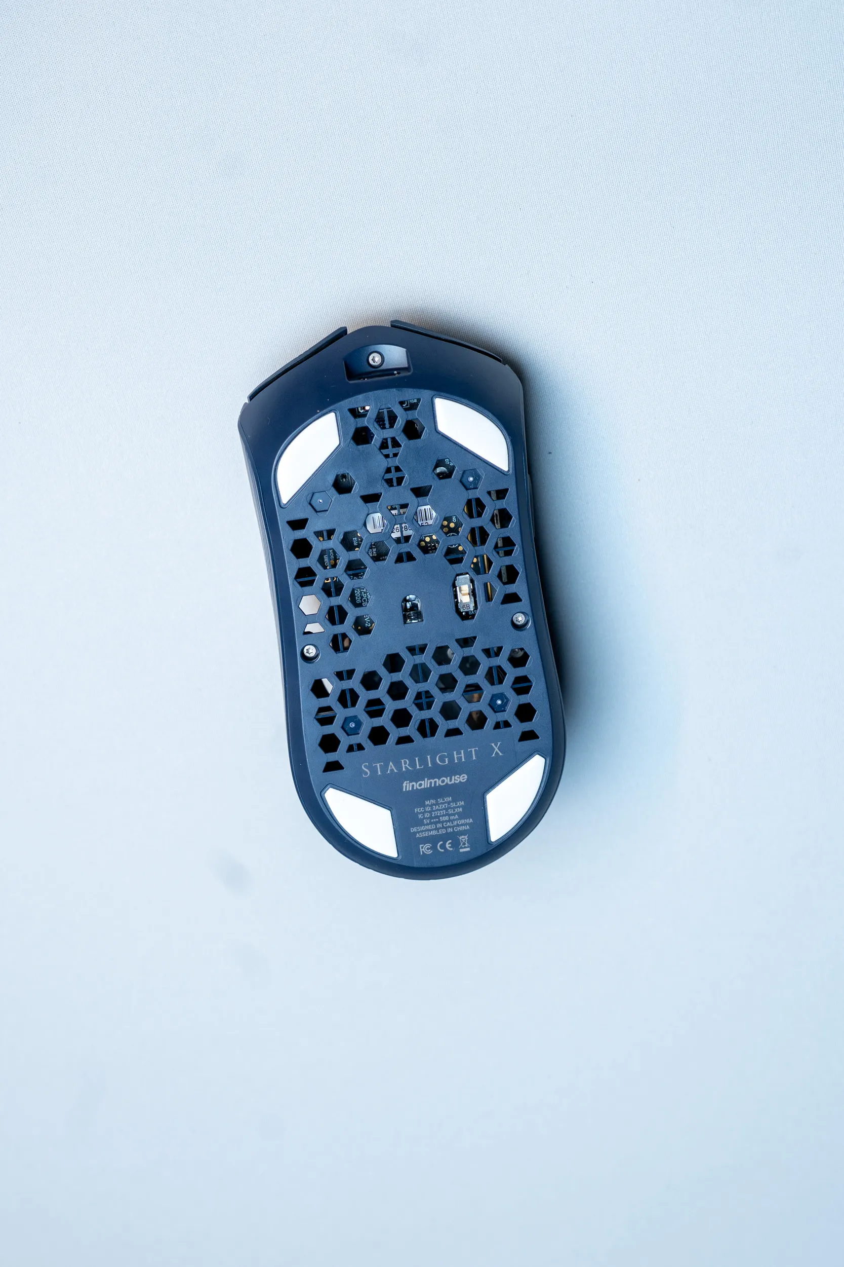 Undersiden av Finalmouse SLX med heksagonmønster, fire hvite skates og Starlight X-logoen
