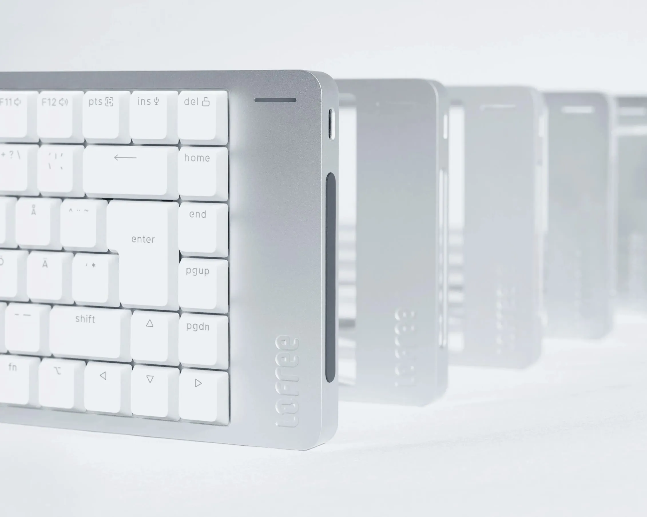 Lofree Flow 2 i hvit, nærbilde av høyre hjørne med nordisk layout og touch-baren på kortsiden, flere tastaturer på rekke bak