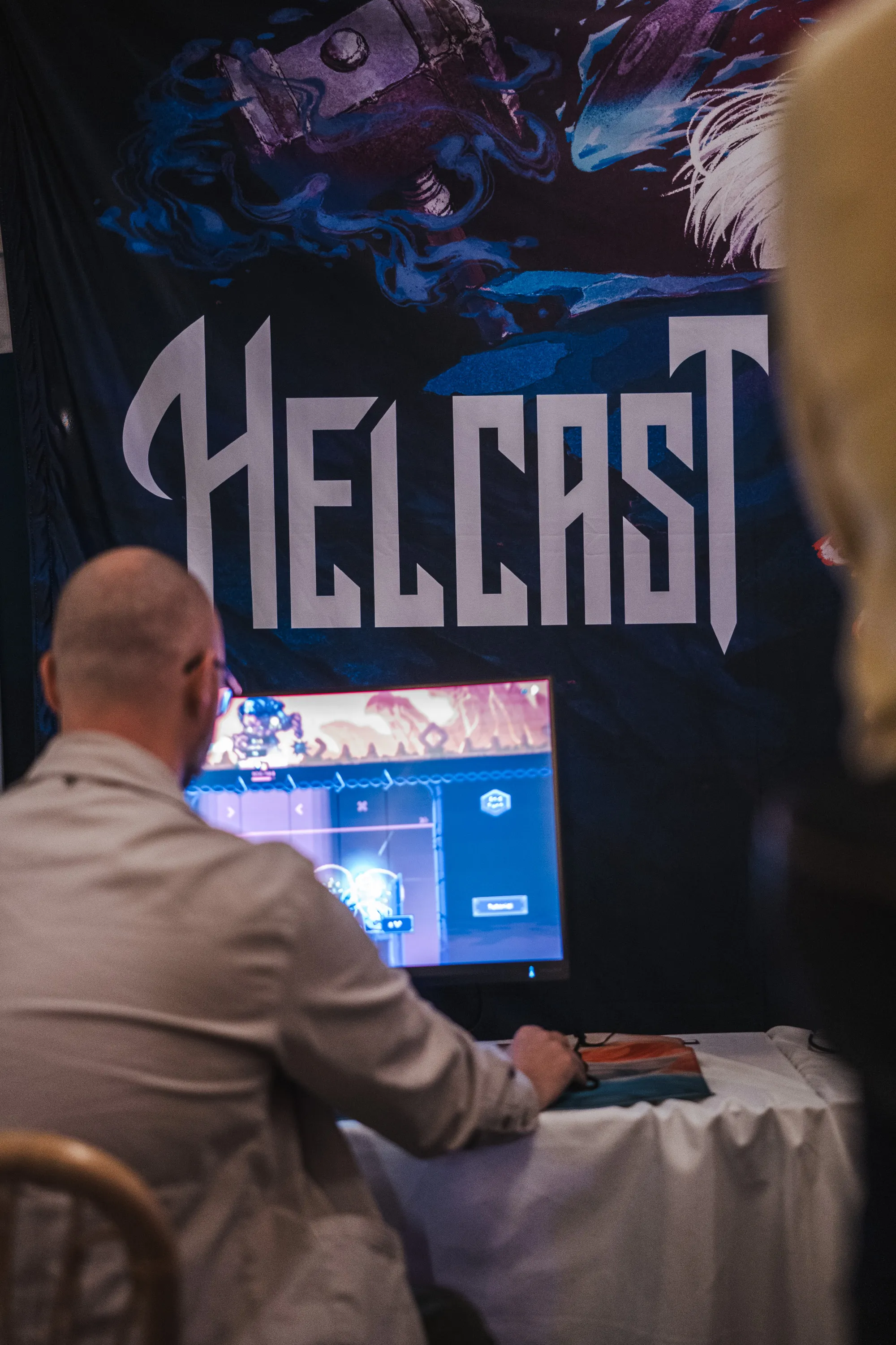 Helcast-banneret over standen på Moderskeppet, med en spiller ved skjermen og en tilskuer i kanten av bildet