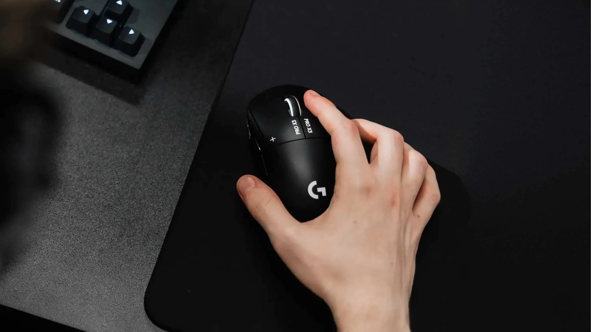 Hånd i clawgrep på Logitech G Pro X3 Superstrike i Midnight Black på en mørk musematte